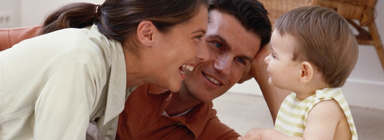 Mother and father smilling at their baby.